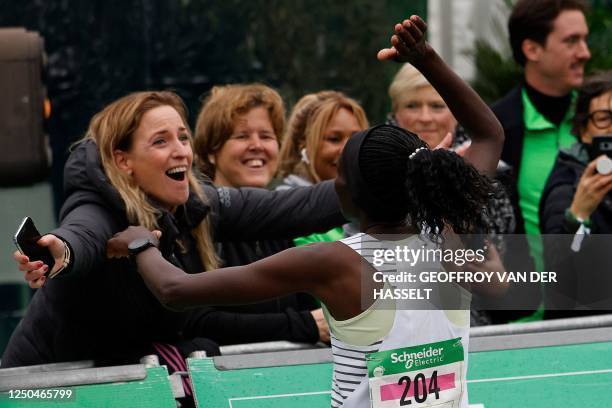 Kenya's Helah Kiprop is congratulated after crossing the finish line at the Arc de Triomphe to win the women's 2023 Paris Marathon, in Paris on April...