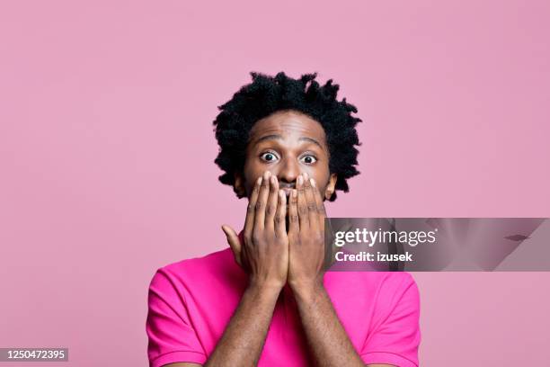 headshot of surprised young man wearing pink polo shirt - hands covering mouth stock pictures, royalty-free photos & images