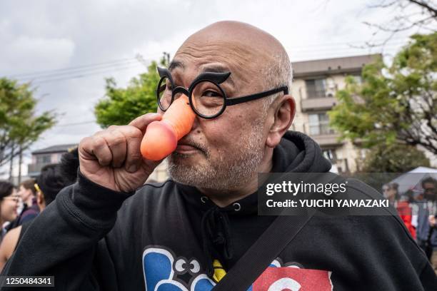 Graphic content / A man wearing a phallic-shaped nose mask poses for photographs during the Kanamara festival in Kawasaki on April 2, 2023.