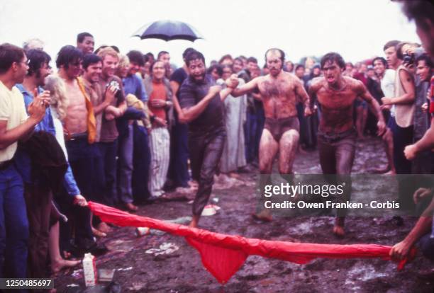 People running to jump into the mud at the Woodstock Music Festival, 1969