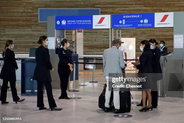 Air France employees wearing protective face masks check a passenger at Paris Charles de Gaulle airport on June 18, 2020 in Roissy-en-France, France....