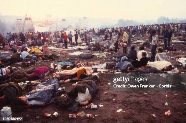 People sleeping and relaxing in the messy field at the Woodstock Music Festival, 1969