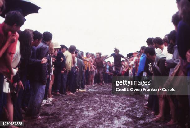 People running to jump into the mud at the Woodstock Music Festival, 1969