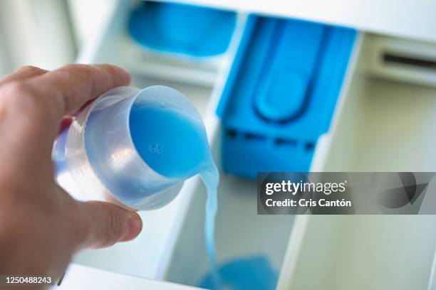 hand adding softener to washing machine - laundry detergent stock-fotos und bilder