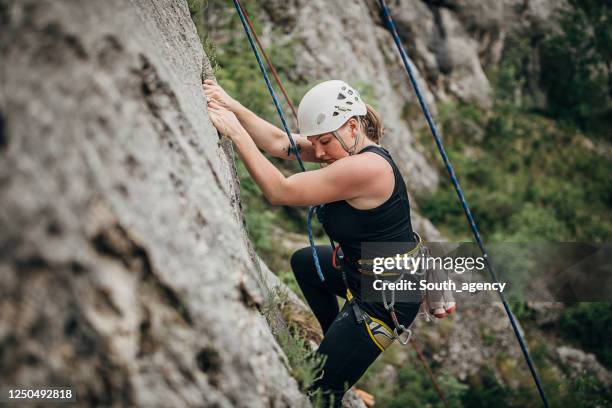 one strong young climber woman climbing on the rock - rock climbing stock pictures, royalty-free photos & images