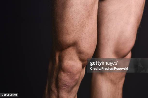 flexing leg muscles over dark studio background - menschlicher muskel stock-fotos und bilder