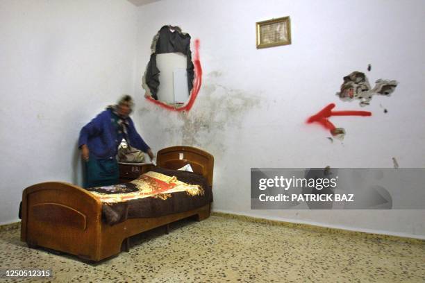 Palestinian woman makes her bed 18 March 2002 under graffiti painted by Israeli soldiers in the al-Amari refugee camp in the West Bank city of...