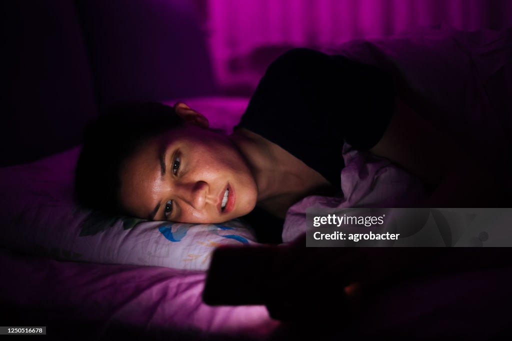 Woman laying in bed and using smart phone