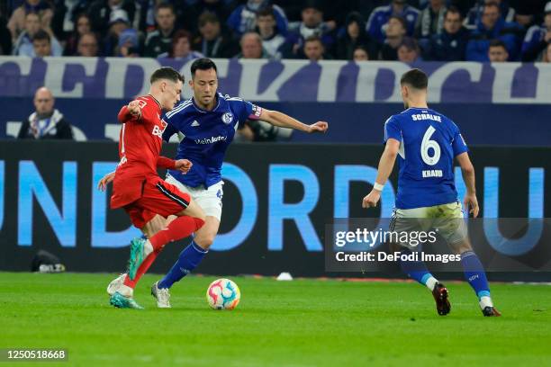 Florian Wirtz of Bayer 04 Leverkusen, Maya Yoshida of FC Schalke 04 and Tom Krauß of FC Schalke 04 battle for the Ball during the Bundesliga match...