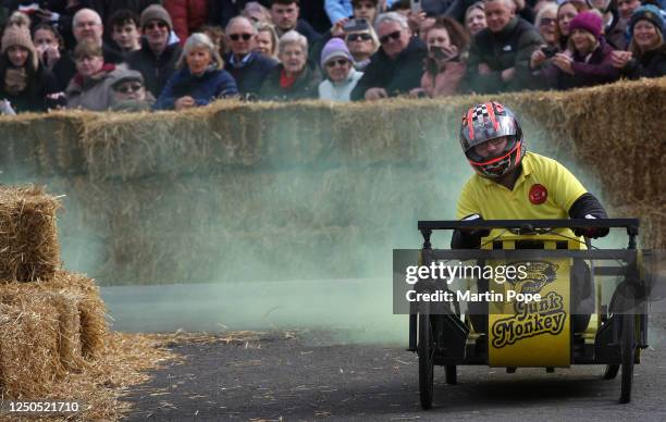 Driver trailing yellow smoke comes round the last bend on the course as part of the 70 year anniversary soap box derby on April 02, 2023 in...