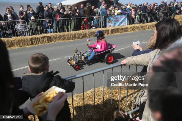 Spectators eat chips and take photos during the 70 year anniversary soap box derby on April 02, 2023 in Hunstanton, England. Over 40 home built karts...