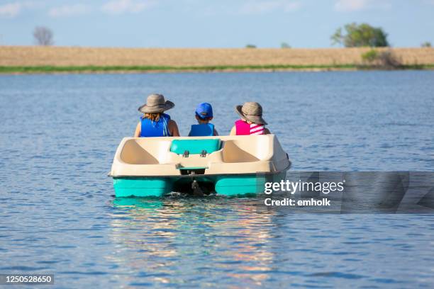 rear view of three children in paddle boat on small lake - paddleboat stock pictures, royalty-free photos & images