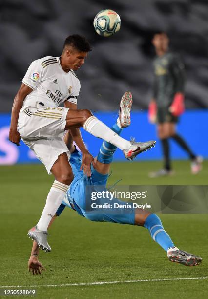 Raphaël Varane of Real Madrid CF fouls Maximiliano Gómez of Valencia CF during the Liga match between Real Madrid CF and Valencia CF at Estadio...