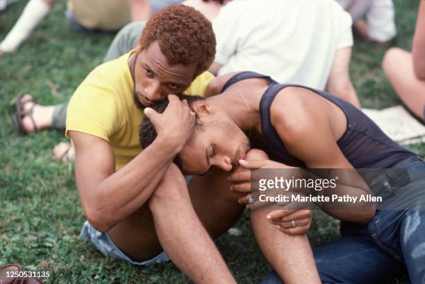 Portrait of an unidentified couple, one with his head on the other's knees, as they sit on the grass during the New York City Pride March, New York,...