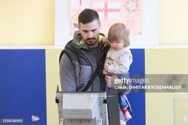 Man with a child casts his ballot at a polling station during the country's parliamentary elections in Sofia on April 2, 2023.