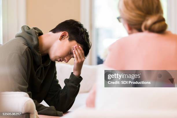 de jongen van de tiener zet hoofd in hand als moederlezingen - berispen stockfoto's en -beelden