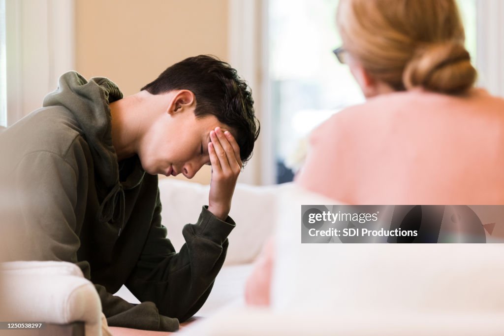 Teen boy puts head in hand as mother lectures