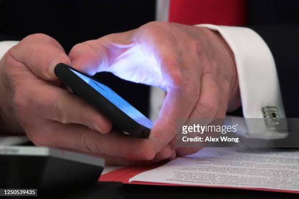 President Donald Trump holds his phone during a roundtable at the State Dining Room of the White House June 18, 2020 in Washington, DC. President...