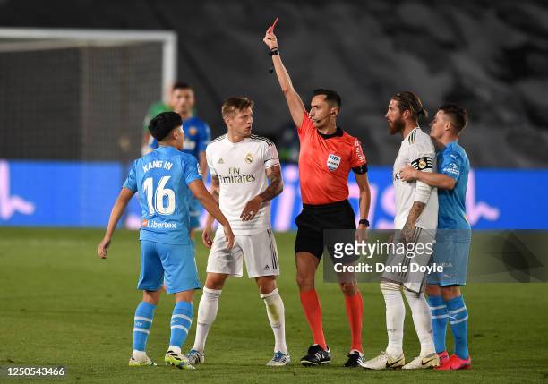 Lee Kang-In of Valencia CF is shown a red card by referee José María Sánchez Martínez after a tackle on Sergio Ramos of Real Madrid CF during the...