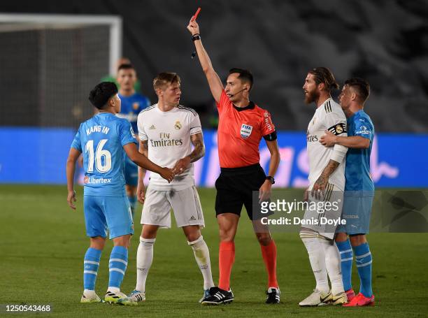 Lee Kang-In of Valencia CF is shown a red card by referee José María Sánchez Martínez after a tackle on Sergio Ramos of Real Madrid CF during the...