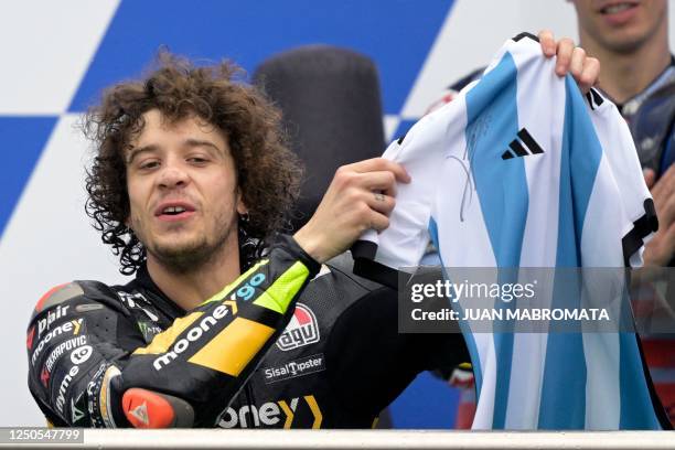 Ducati Italian rider Marco Bezzecchi shows the Argentine jersey signed by Lionel Messi he was presented for his first win, on the podium of the...