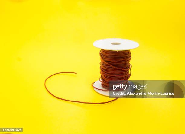 dark red waxed thread on a yellow background - cable spool stock pictures, royalty-free photos & images