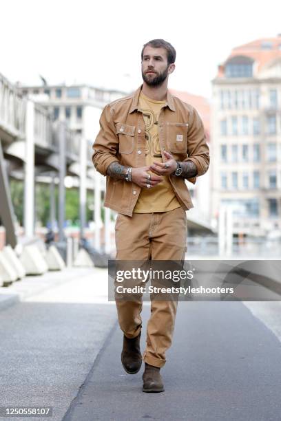 Influencer and model Andre Hamann, wearing a caramel colored jacket by Mother, matching caramel colored pants by Mother, a mustard colored t-shirt...