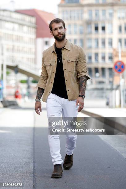 Influencer and model Andre Hamann, wearing a beige shirt by Belstaff, a black t-shirt by Topman, white denim jeans by Calvin Klein, jewelry by Haze &...