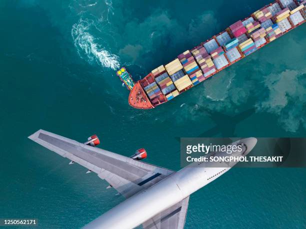 aerial view/the plane flew past a cargo ship that was leaving the harbor, with a truckboat spinning a large ship. business and transportation are being driven after the effects of the coronal virus, or covid-19 - airport traffic stockfoto's en -beelden