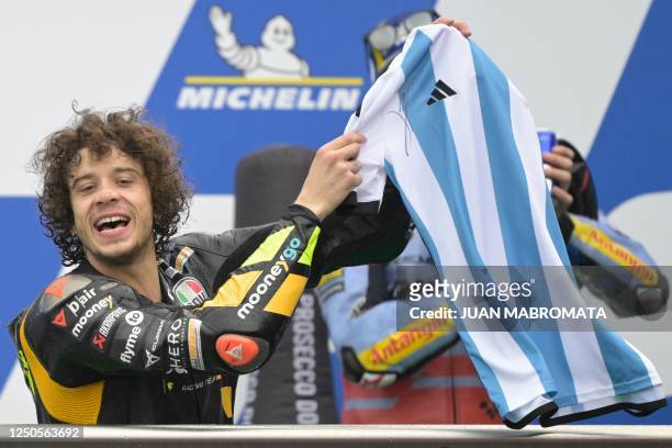 Ducati Italian rider Marco Bezzecchi shows the Argentine jersey signed by Lionel Messi he was presented for his first win, on the podium of the...