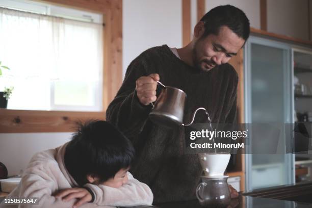 boy looking his father making coffee - kochlehrling stock-fotos und bilder