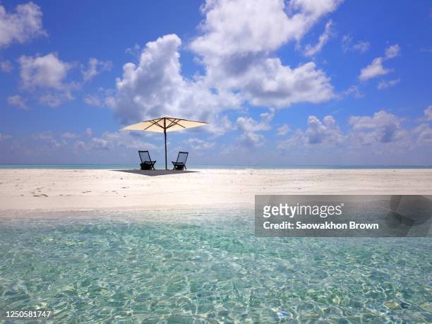 exotic island with a long sandbar, and some beach chairs and a white umbrella on the distance, pacific ocean , fiji - pacific islands - fotografias e filmes do acervo