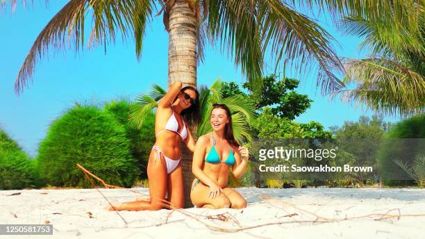 happy woman applying sunscreen on the back of her friend, getting ready for sunbathing on tropical beach in thailand - sunburn tourist stock-fotos und bilder