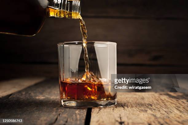 pouring glass of whiskey, close-up whisky on the rocks. - drink photos et images de collection