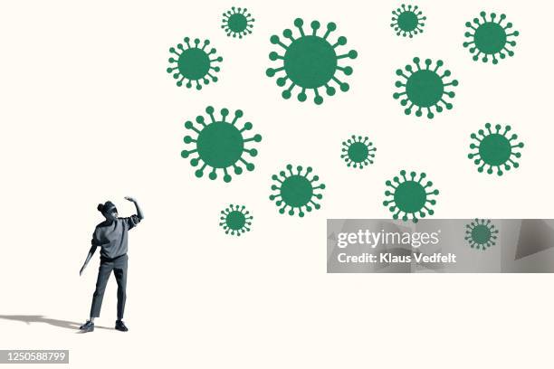 woman shielding eyes by large green coronavirus - epidemie stock pictures, royalty-free photos & images