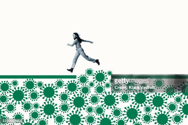 woman jumping over green coronavirus under ramp - respiratory disease stock pictures, royalty-free photos & images