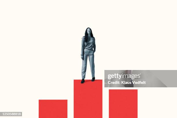smiling woman standing on vibrant red bar graph - infographie production artistique photos et images de collection