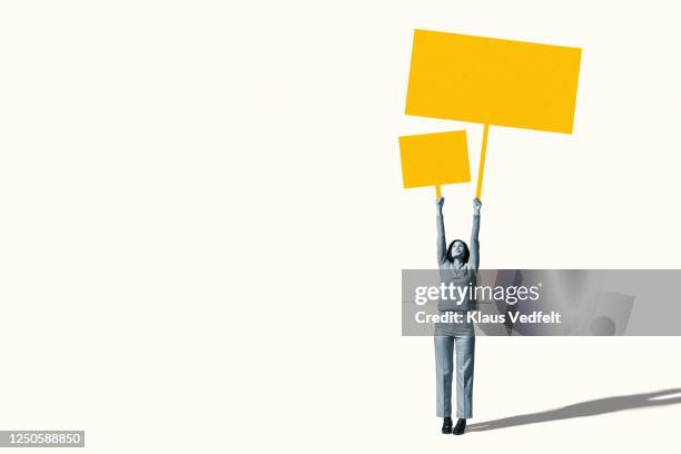 female protestor holding blank yellow placards - revolución fotografías e imágenes de stock