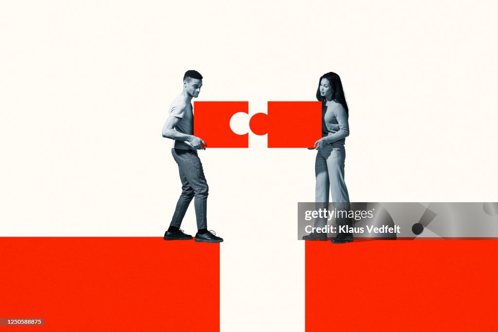Man and woman positioning orange puzzle pieces