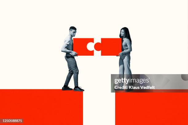 man and woman positioning orange puzzle pieces - problem solving stock pictures, royalty-free photos & images