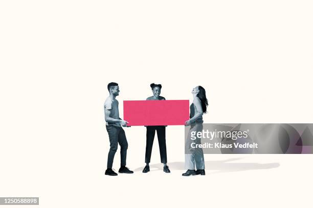 cheerful young friends carrying large pink block - creative collaboration holding stockfoto's en -beelden