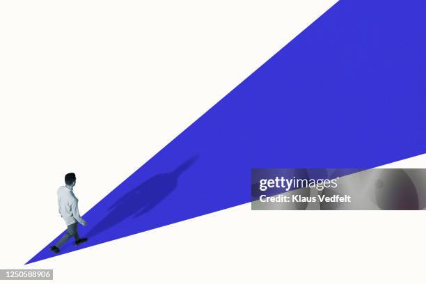 high angle view of young man walking on blue ramp - evolution concept imagens e fotografias de stock