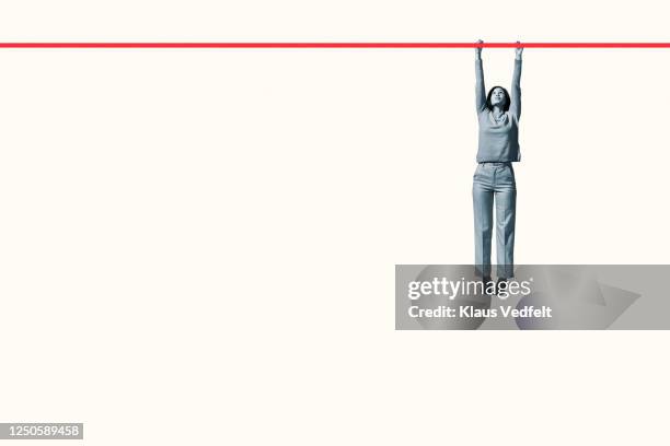 full length of young woman hanging from red rope - hanging rope object stock pictures, royalty-free photos & images