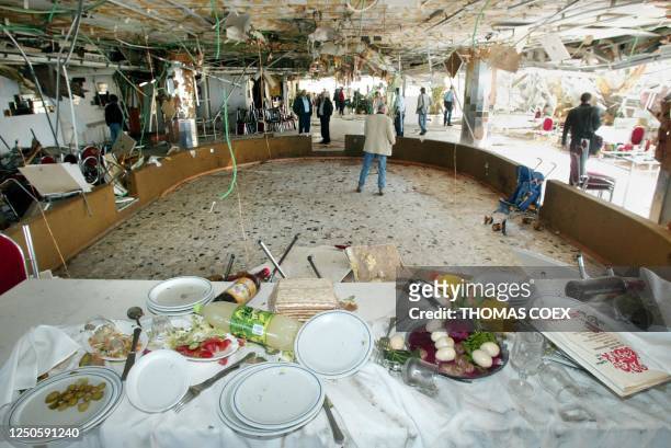 The remains of a Jewish passover meal sit on a table 28 March 2002, following a suicide attack late last night that killed 20 people plus the...
