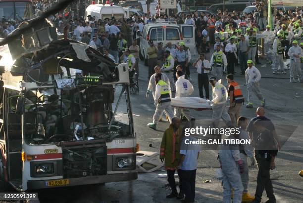 Israeli paramedics carry a body on a strecher next blown up bus that destroyed in a Palestinian suicide attack in Jerusalem 11 June 2003. 16 people...