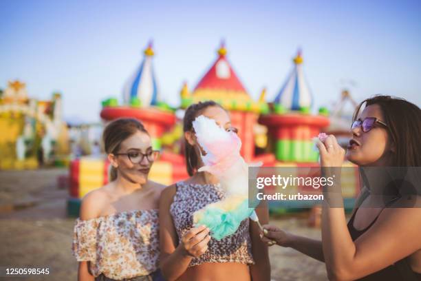 friends eating cotton candy near inflatable castle - bounce castle stock pictures, royalty-free photos & images