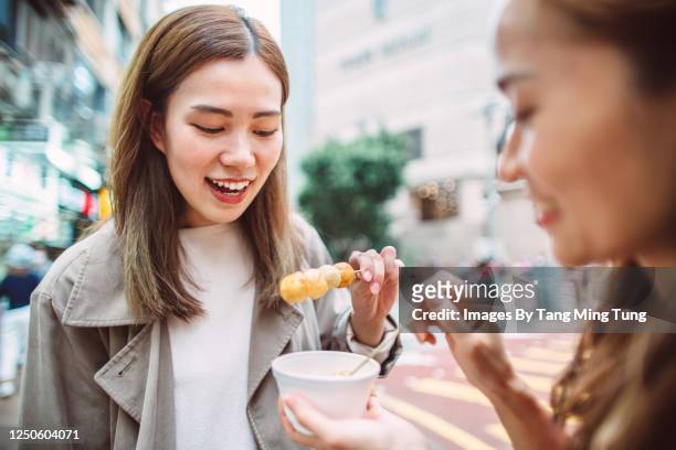young cheerful girlfriends enjoying hong kong local street food joyfully in street - hong kong street food stock pictures, royalty-free photos & images
