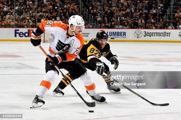 Scott Laughton of the Philadelphia Flyers skates against Sidney Crosby of the Pittsburgh Penguins at PPG PAINTS Arena on April 2, 2023 in Pittsburgh,...