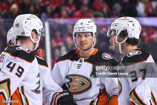 Max Jones, Cam Fowler and Mason McTavish of the Anaheim Ducks confer during a break in play against the Calgary Flames during the first period of an...