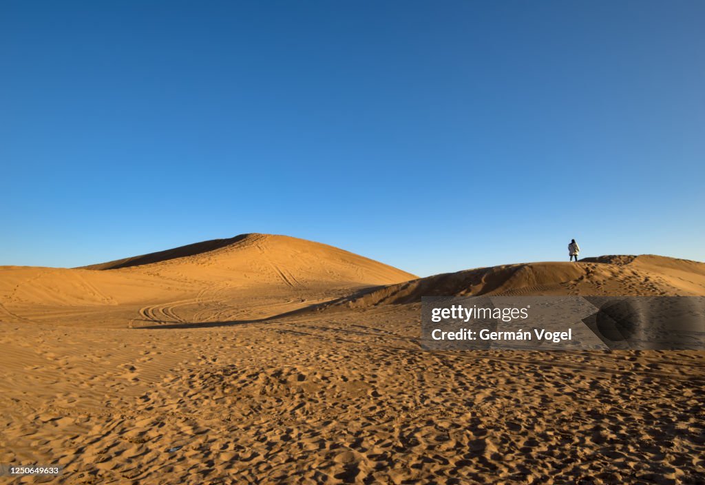 Distant lone person walking among desert dunes, Shabahang, Yazd, Iran